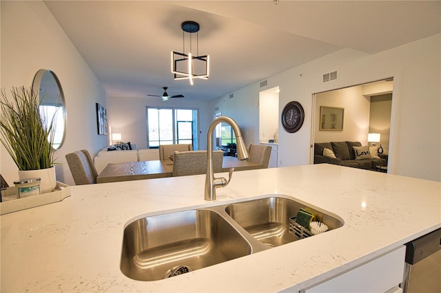 kitchen featuring open floor plan, visible vents, a sink, and light stone countertops