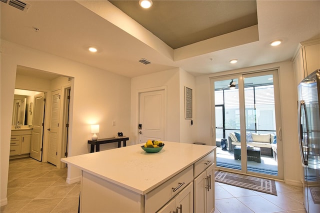 kitchen featuring a raised ceiling, visible vents, freestanding refrigerator, light tile patterned flooring, and a kitchen island