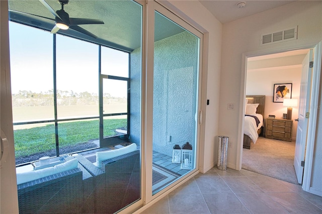 entryway featuring tile patterned flooring, a sunroom, visible vents, a ceiling fan, and carpet