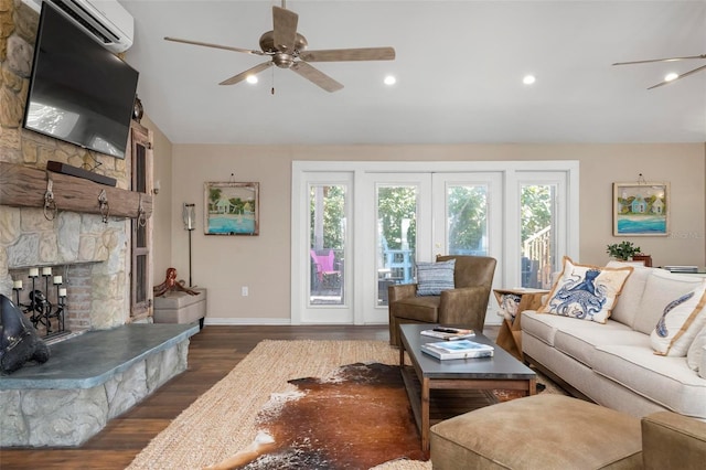 living room featuring a stone fireplace, vaulted ceiling, dark hardwood / wood-style floors, a wall unit AC, and ceiling fan