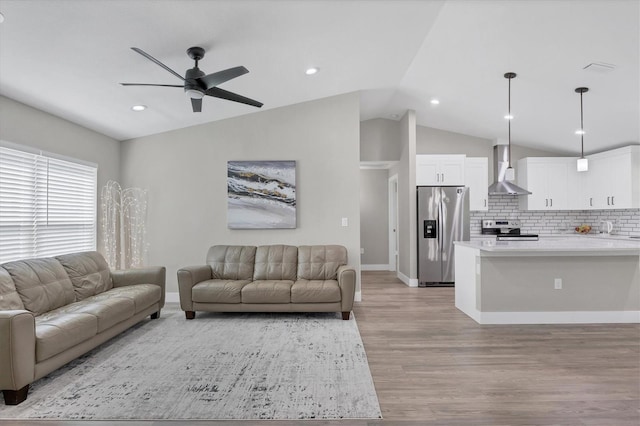 living room featuring vaulted ceiling, ceiling fan, and light hardwood / wood-style flooring