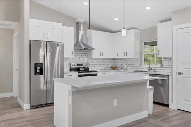 kitchen featuring decorative light fixtures, white cabinetry, a center island, stainless steel appliances, and wall chimney exhaust hood