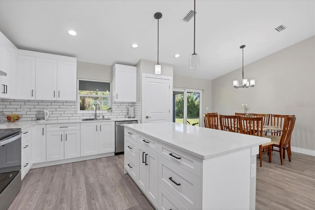 kitchen with stainless steel appliances, decorative light fixtures, sink, and white cabinets