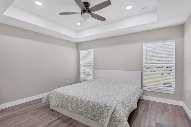 bedroom featuring a tray ceiling, ceiling fan, and hardwood / wood-style flooring