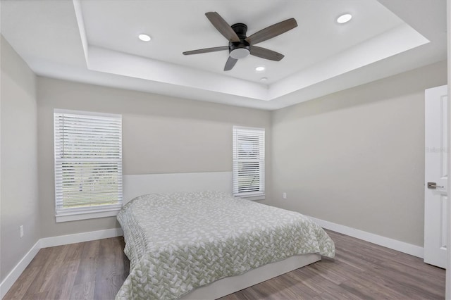 bedroom featuring a raised ceiling, hardwood / wood-style floors, and ceiling fan