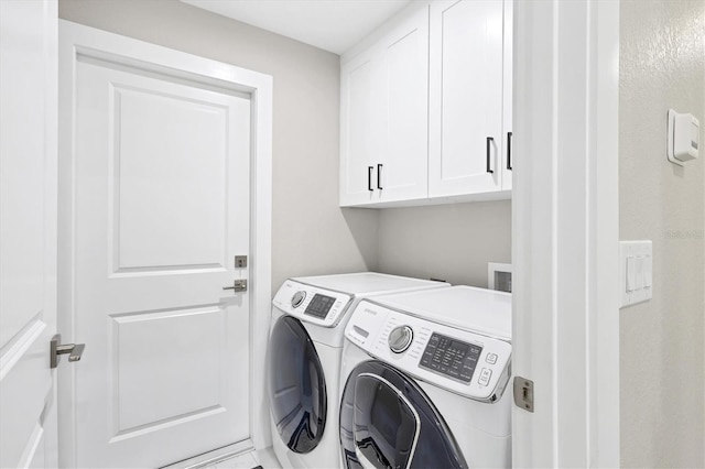 clothes washing area featuring cabinets and washing machine and dryer