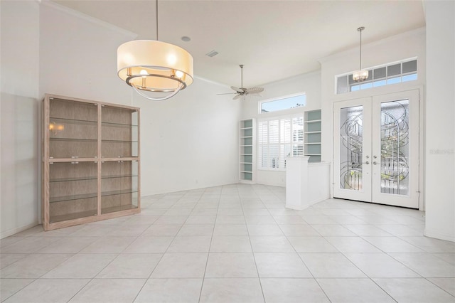 interior space with french doors, light tile patterned floors, ceiling fan, crown molding, and built in shelves