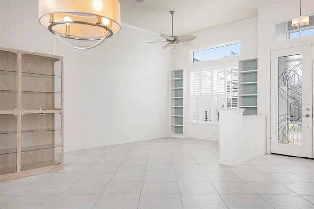 foyer entrance featuring ceiling fan with notable chandelier, ornamental molding, and light tile patterned flooring