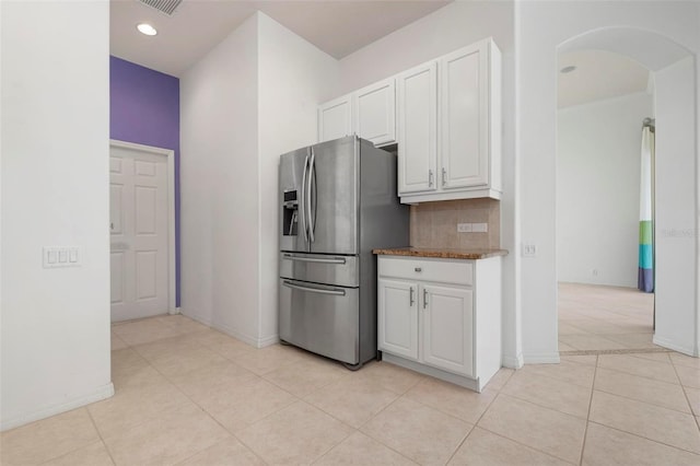 kitchen with stainless steel refrigerator with ice dispenser, backsplash, light tile patterned floors, and white cabinets