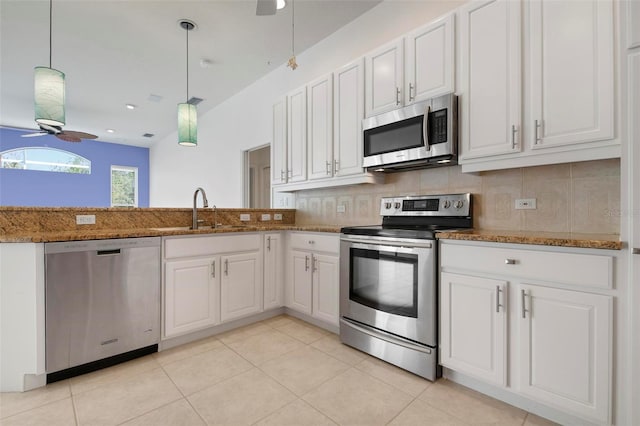 kitchen featuring appliances with stainless steel finishes, pendant lighting, ceiling fan, dark stone counters, and white cabinets