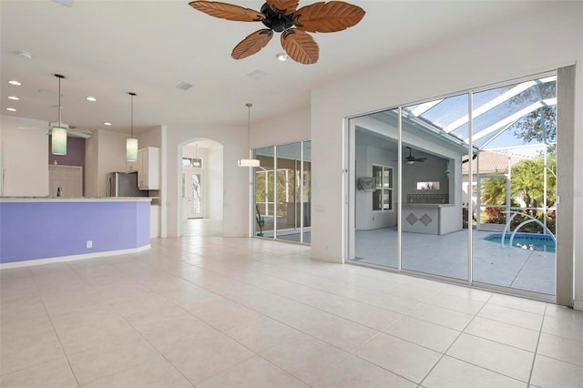 unfurnished room with a wealth of natural light, ceiling fan, and light tile patterned floors