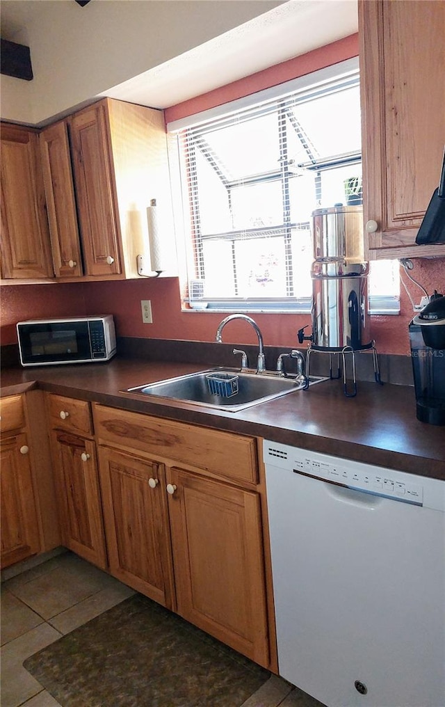 kitchen featuring white dishwasher, sink, and dark tile patterned floors