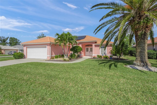 view of front of property with a garage, a front yard, and solar panels