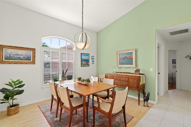 dining room featuring high vaulted ceiling and light hardwood / wood-style flooring