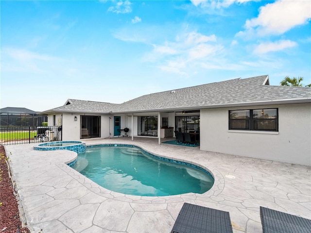 view of pool with a patio, fence, and a pool with connected hot tub