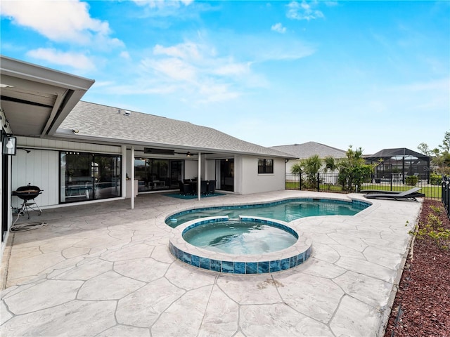 view of pool featuring a pool with connected hot tub, a patio area, a grill, and fence