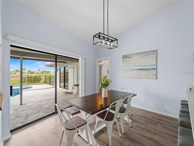 dining area featuring lofted ceiling, baseboards, and wood finished floors