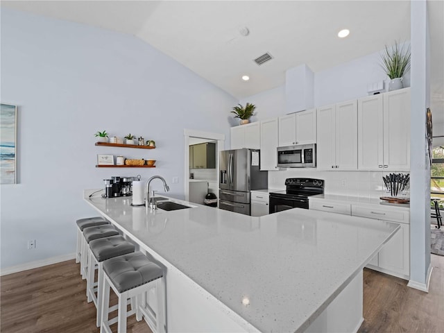 kitchen featuring a sink, visible vents, appliances with stainless steel finishes, open shelves, and a kitchen bar