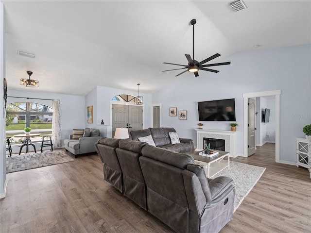 living room featuring lofted ceiling, a fireplace, wood finished floors, and visible vents