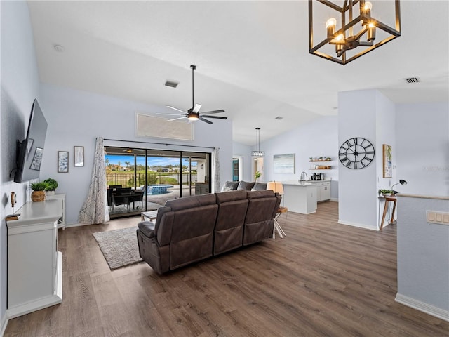 living room featuring visible vents, vaulted ceiling, dark wood-style flooring, and ceiling fan with notable chandelier