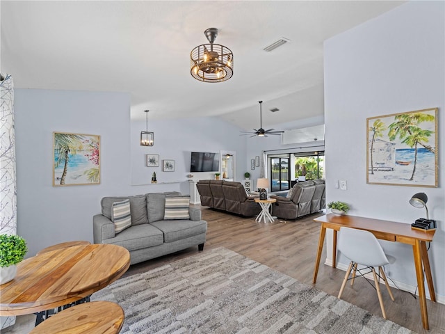 living room with lofted ceiling, ceiling fan with notable chandelier, wood finished floors, visible vents, and baseboards