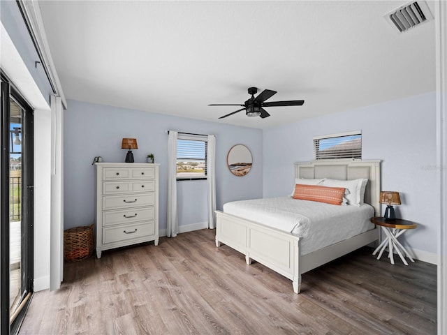 bedroom featuring a ceiling fan, wood finished floors, visible vents, and baseboards