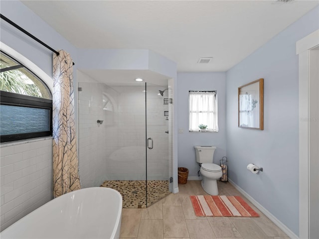 bathroom with visible vents, a freestanding bath, toilet, a shower stall, and baseboards