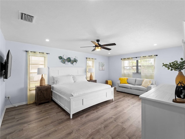 bedroom featuring dark wood-style floors, multiple windows, visible vents, and recessed lighting