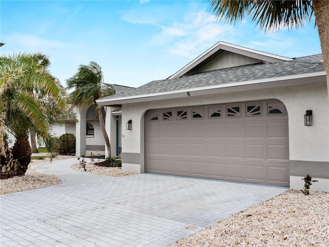 ranch-style home with a shingled roof, an attached garage, and stucco siding