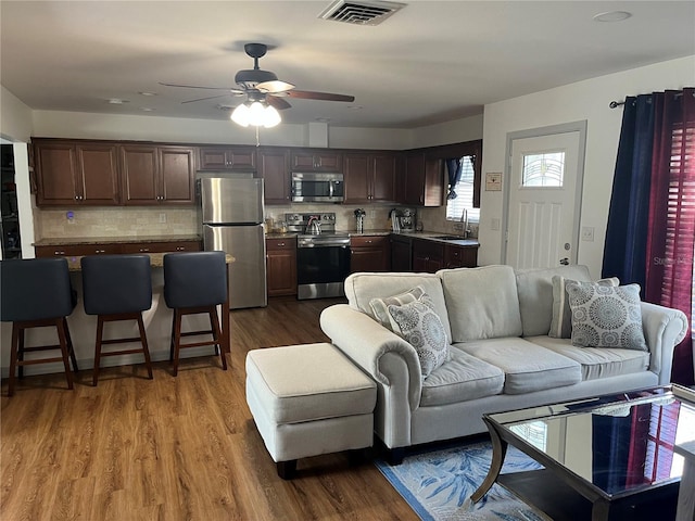 living room with sink, dark wood-type flooring, and ceiling fan