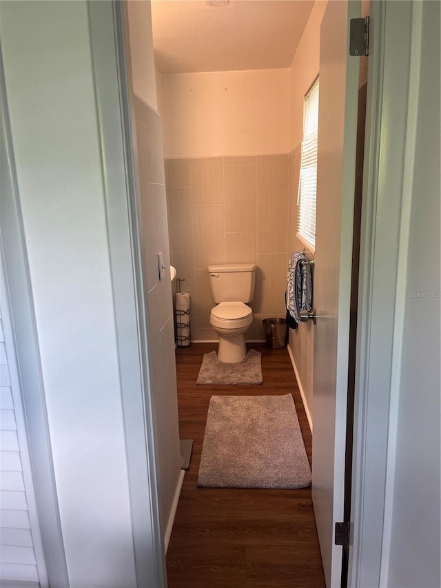 bathroom featuring hardwood / wood-style flooring, tile walls, and toilet