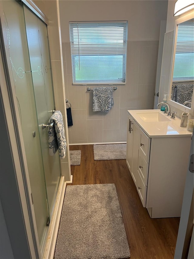 bathroom featuring vanity, hardwood / wood-style floors, tile walls, and walk in shower