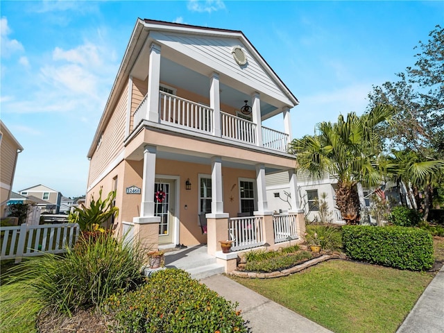 view of front of house with a front yard, a balcony, and a porch