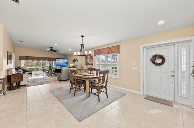 dining space with light tile patterned flooring, plenty of natural light, and ceiling fan with notable chandelier