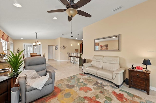 tiled living room with ceiling fan with notable chandelier