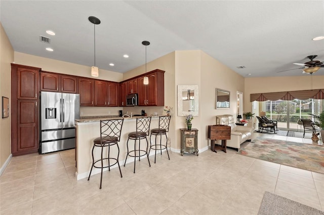 kitchen with a kitchen bar, kitchen peninsula, pendant lighting, ceiling fan, and stainless steel appliances