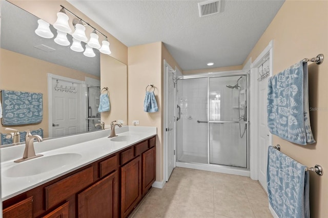 bathroom with vanity, tile patterned floors, a textured ceiling, and a shower with shower door