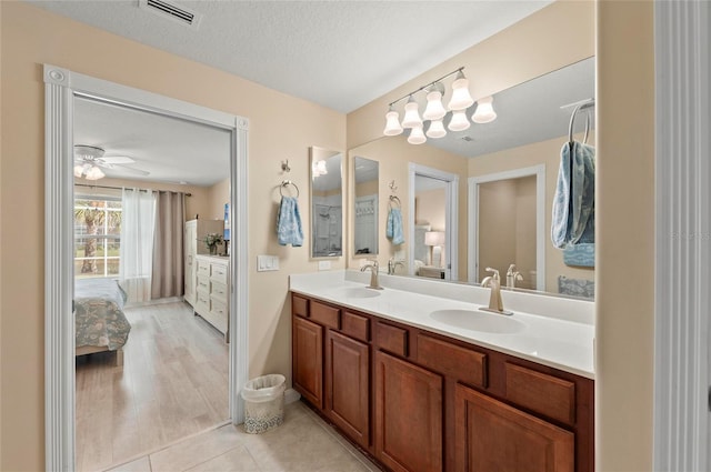 bathroom with ceiling fan, vanity, tile patterned flooring, and a textured ceiling