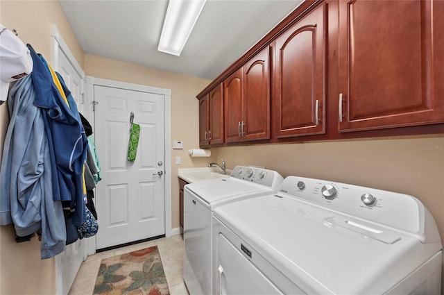 clothes washing area featuring sink, cabinets, a textured ceiling, light tile patterned floors, and washer and clothes dryer