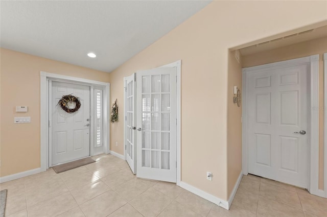 entryway with lofted ceiling and light tile patterned floors