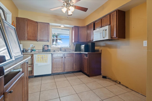 kitchen with sink, light stone counters, white appliances, light tile patterned floors, and ceiling fan