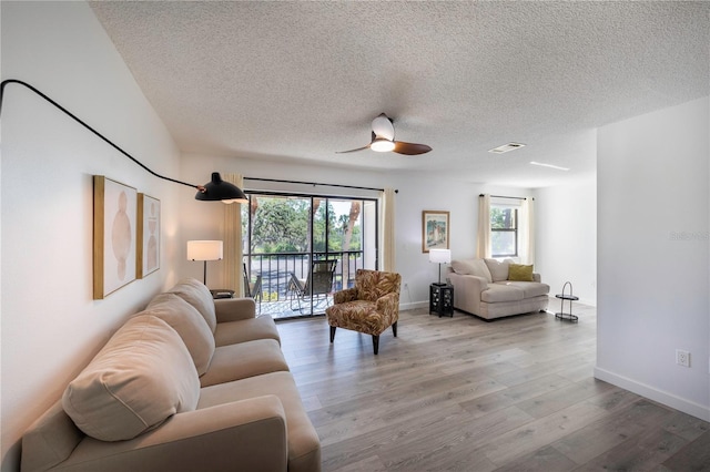 living room featuring visible vents, a textured ceiling, and wood finished floors