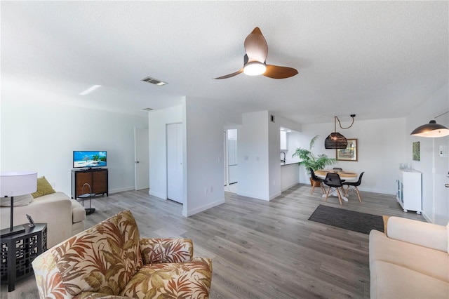 living room featuring visible vents, a textured ceiling, and light wood-style flooring