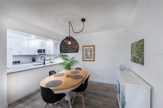 dining area featuring a textured ceiling, baseboards, and wood finished floors