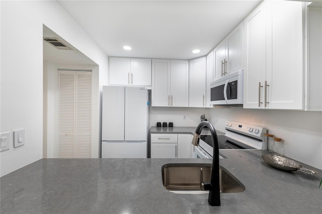 kitchen featuring recessed lighting, white appliances, a sink, visible vents, and white cabinets