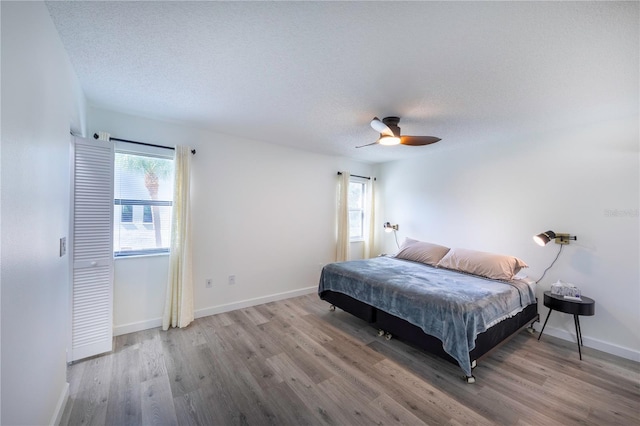 bedroom with a textured ceiling, baseboards, and wood finished floors