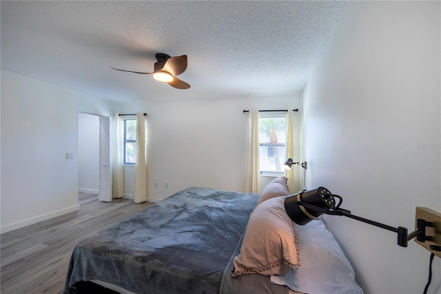 bedroom featuring a textured ceiling, multiple windows, and wood finished floors