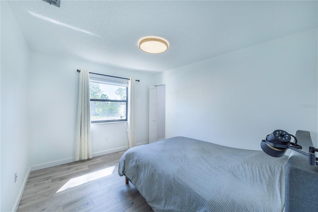 bedroom featuring a textured ceiling, baseboards, and wood finished floors