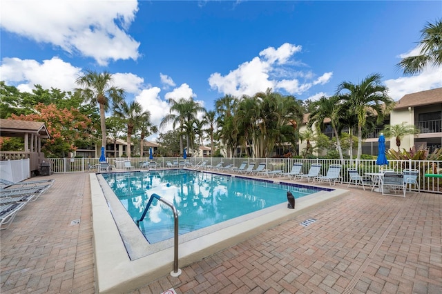 community pool with a patio area and fence