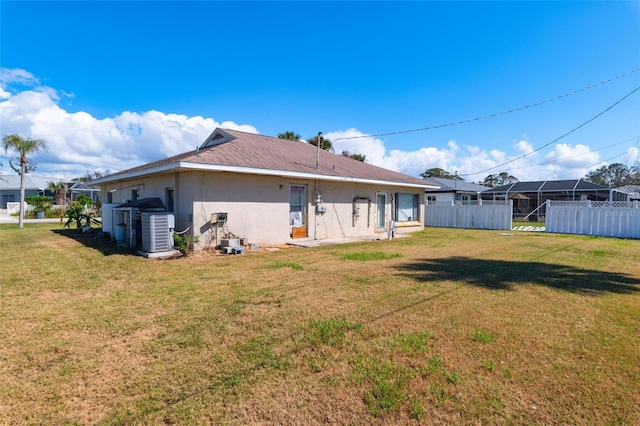 rear view of house with central AC and a lawn